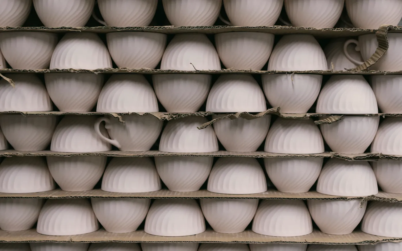 Rows of white porcelain bowls on production racks